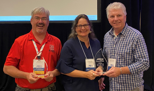 Image of three people posing with awards